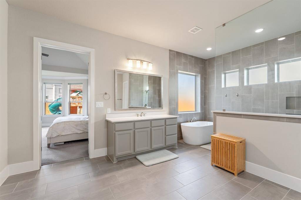 Step into the beautiful primary bathroom, featuring a spacious double vanity with plenty of storage space. Relax and unwind in the large soaking tub, or enjoy the walk-in shower with a sleek glass surround. The upgraded lighting adds a touch of elegance, creating a spa-like atmosphere that’s perfect for your daily routine.