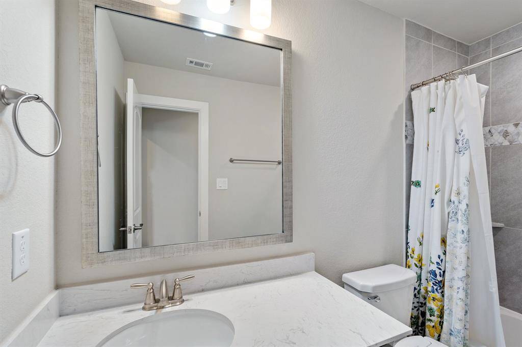This private secondary bathroom features a tub/shower combo, offering versatility and comfort. The sleek engineered stone countertops add a contemporary flair, while the neutral colors create a serene, inviting space. It’s an ideal bathroom for family members or guests seeking a relaxing retreat.