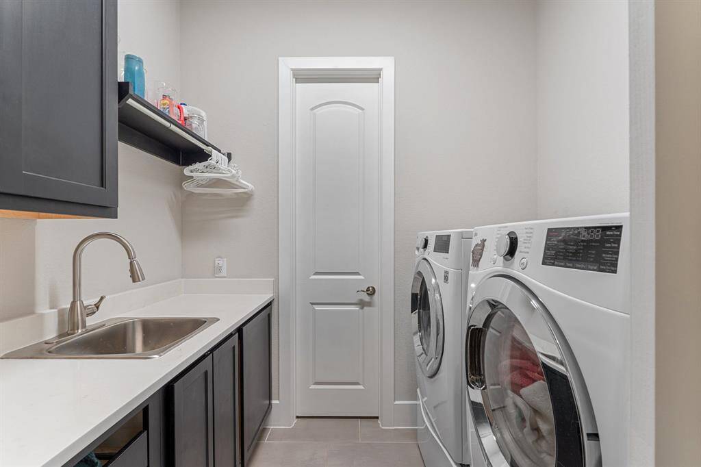 Functional laundry room with a sink, warm cabinetry, built-in storage and linen closet.