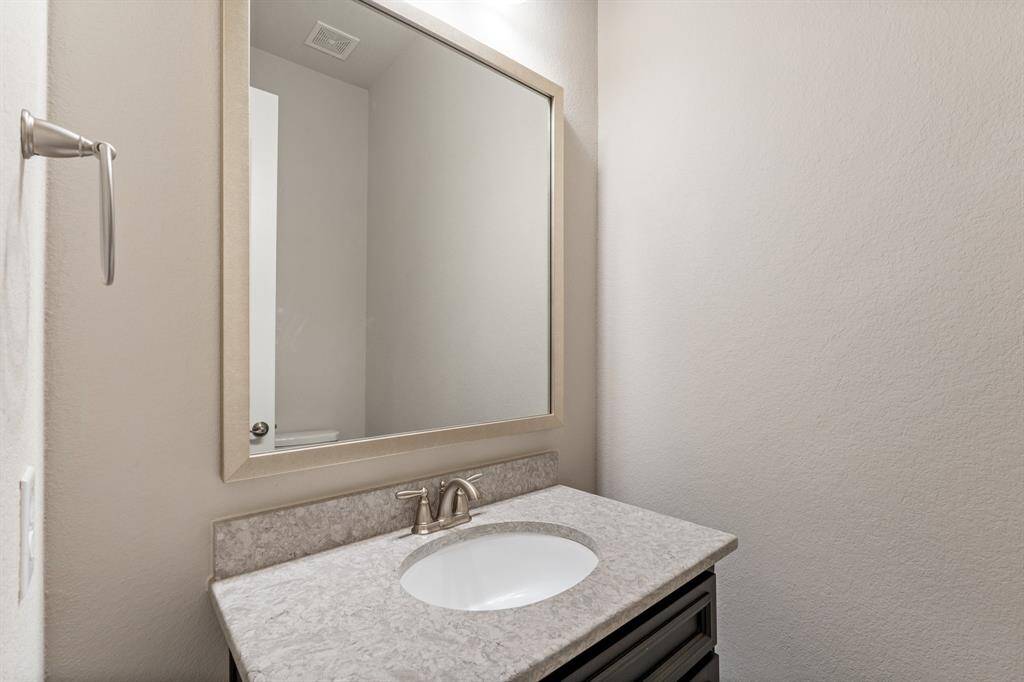 Powder room under the stairs on the main floor, featuring a sleek vanity and modern finishes, offering both style and functionality for guests.
