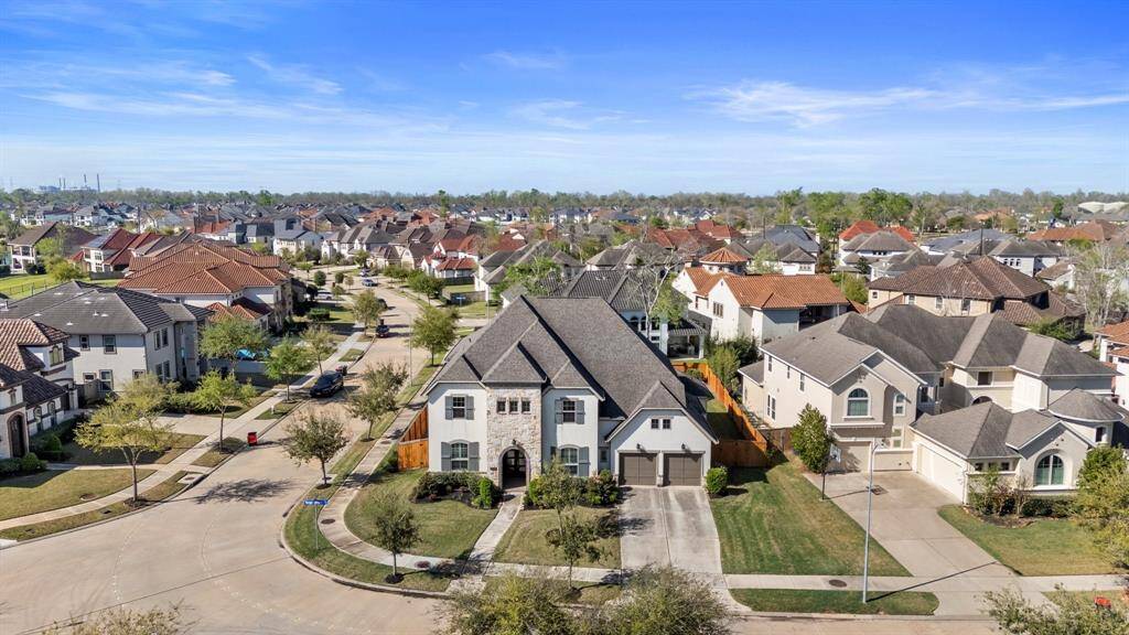 This aerial view highlights the spacious corner lot, showcasing the expansive front yard that offers both curb appeal and privacy. The large, open space creates a welcoming first impression and provides endless potential for landscaping or personal touches, making it a perfect setting for a beautiful home.