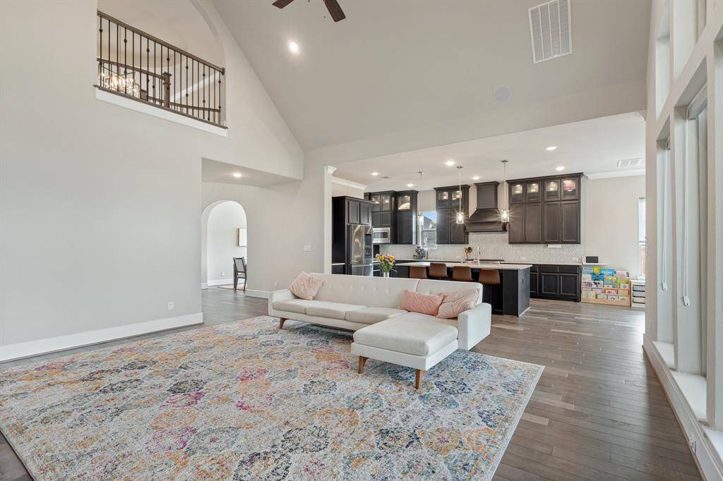 This spacious living room seamlessly connects with the entryway, dining room, and gourmet kitchen, creating an open, airy floorplan ideal for entertaining. The upstairs balcony adds an elegant touch to the overall design.