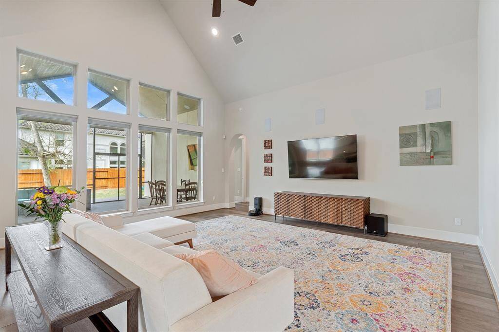 A WALL OF WINDOWS offers a seamless view of the screened in outdoor living area. The vaulted ceiling, neutral finishes and abundant natural light enhance the welcoming atmosphere.