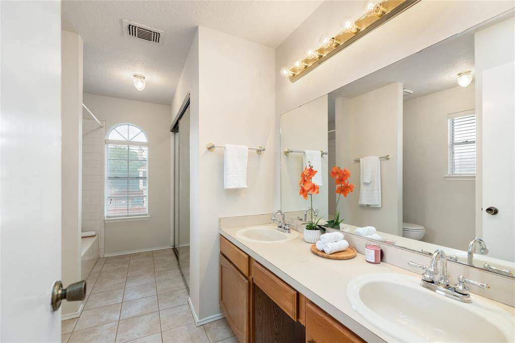 Primary bathroom has large windows, double sinks, tub/shower combo, and dual closets.