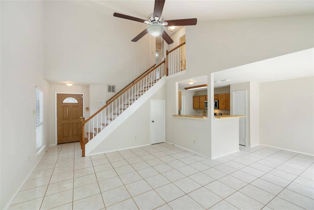 The view from the edge of the living room at the front door, kitchen, and the stairs to the second floor.
