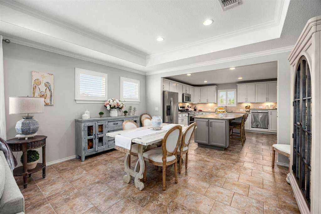 The photo showcases the bright and open dining area connected to the modern updated kitchen. The space features elegant cabinetry, a central island, and stainless steel appliances, with neutral tones and stylish decor, creating a welcoming atmosphere.