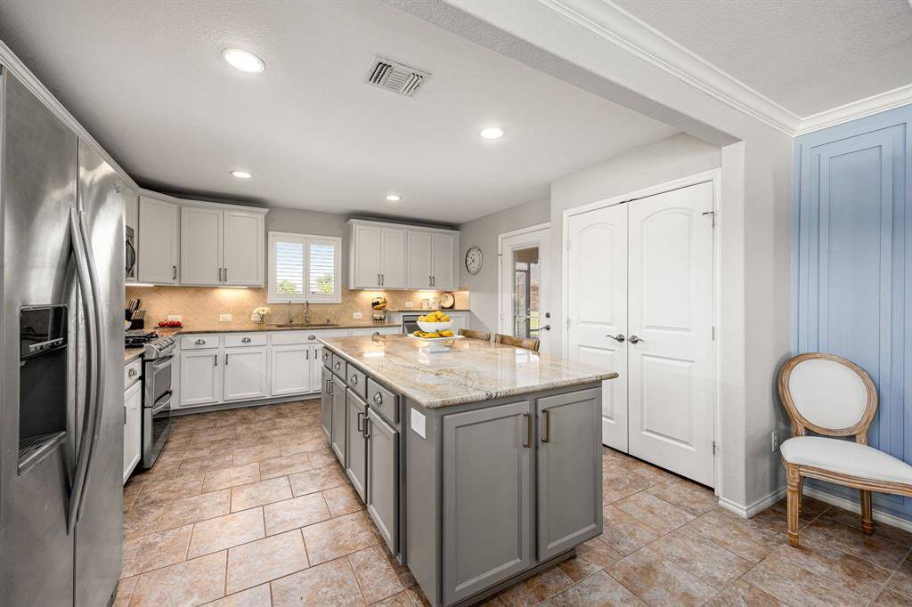 This kitchen features a spacious, modern design with a large central island, stainless steel appliances, and light cabinetry.