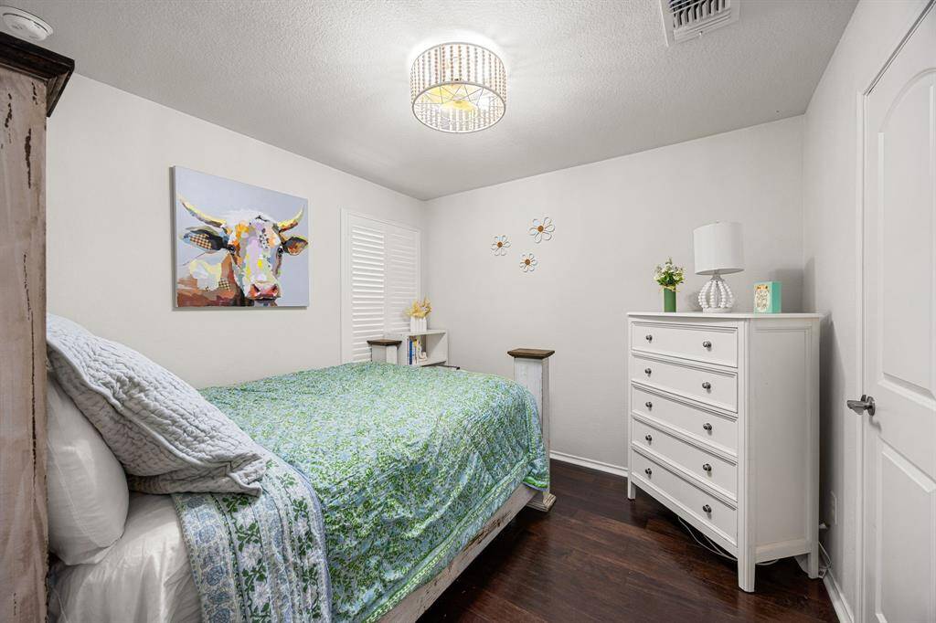 One of the secondary bedrooms with wood floor, plantation shutters and wood beaded chandelier ceiling fan with light and remote.