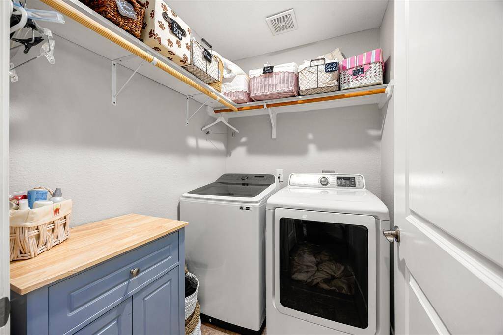 The laundry room features overhead shelving for storage.
