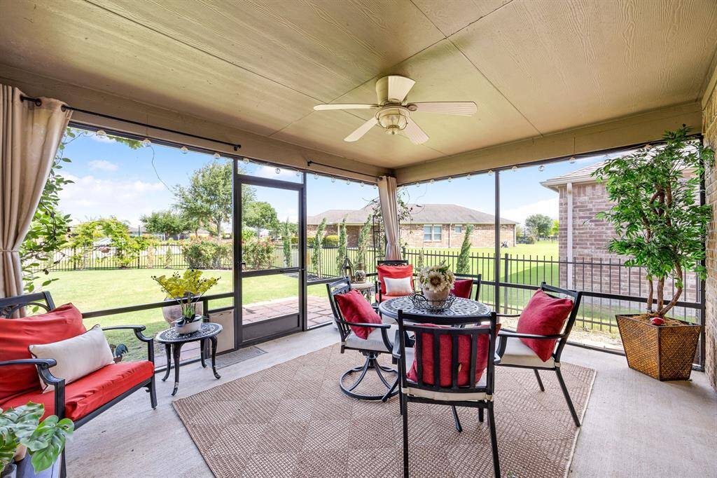 This inviting screened-in patio features a ceiling fan with light with remote, and views of a lush backyard. Ideal for relaxing or entertaining, it seamlessly blends indoor and outdoor living.