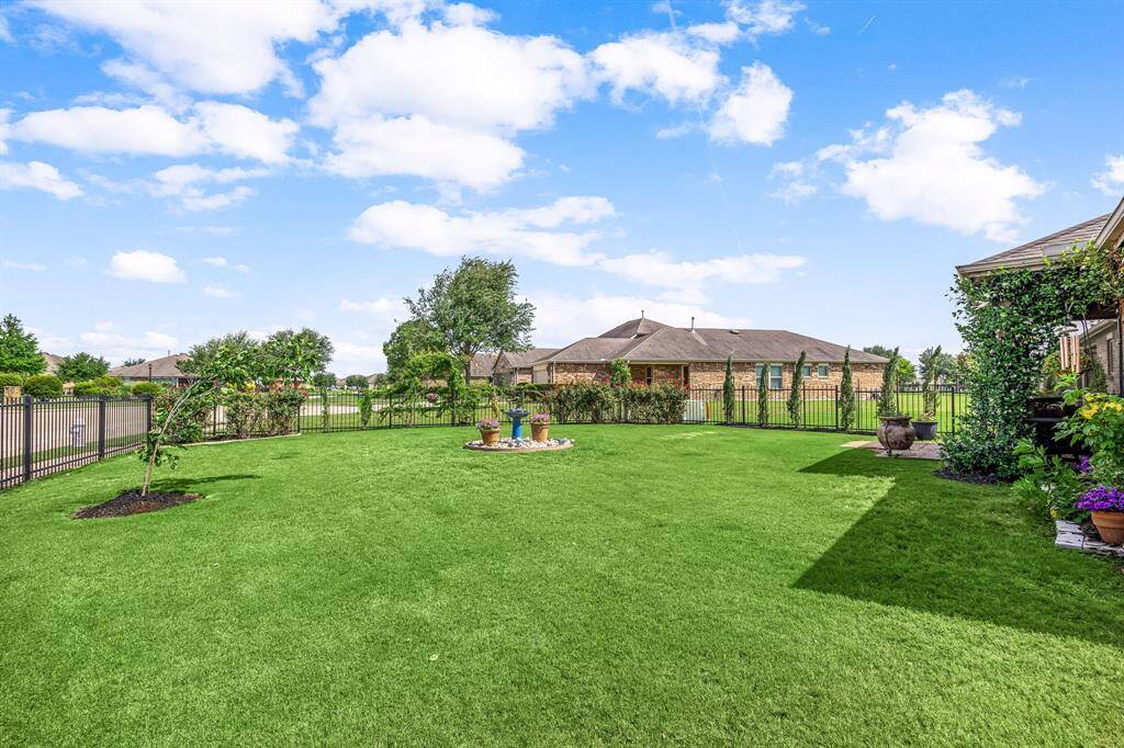 The spacious backyard is surrounded completely by a rod iron fence. The area offerins a serene outdoor space ideal for relaxation or entertaining.