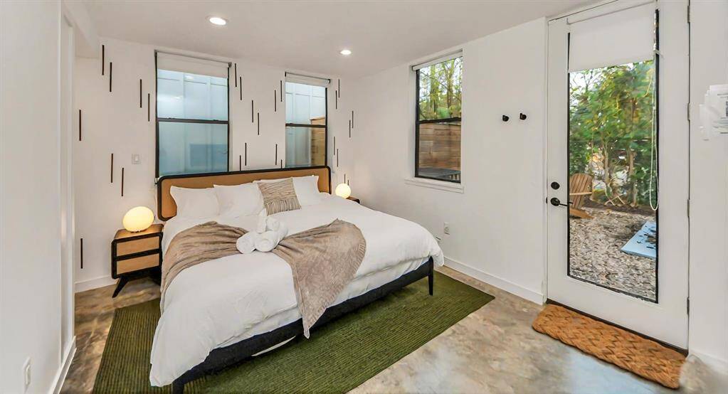 First floor bedroom offers concrete floors, private access to backyard, and pull down shades for privacy.