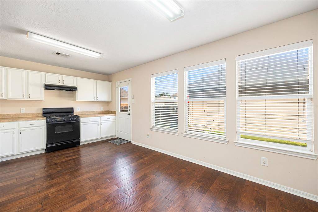 The kitchen features generous white cabinet space and a clear view of the private, fully fenced backyard through the large windows
