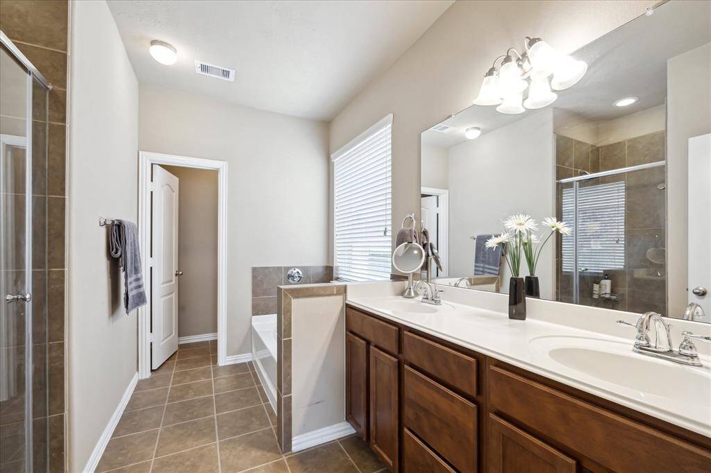 Elegant primary bathroom boasts double sinks with ample counter space, a separate soaking tub, and a spacious walk-in shower—combining functionality and luxury for your daily routine and relaxation.