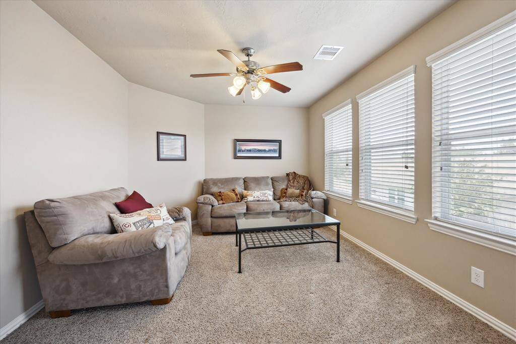 Versatile upstairs flex space serves as a game room, study, media room, or more. Featuring a ceiling fan and a wall of three windows, this bright and spacious area adapts to your lifestyle needs with comfort and natural light.