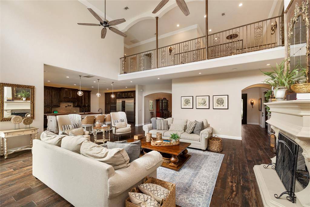 A sweeping balcony from the second floor overlooks the grand living room below, creating a dramatic open-concept feel. Elegant arched doorways from both the entry and formal dining room add architectural charm and timeless sophistication.
