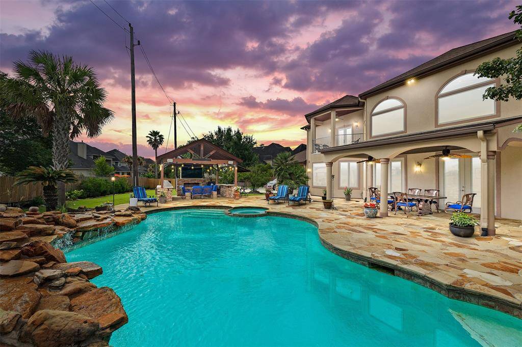 An exquisite private oasis awaits. The resort-style pool features a tranquil waterfall, surrounded by flagstone decking, a covered outdoor kitchen, and a balcony that overlooks the lush backyard retreat—perfect for serene mornings or sophisticated entertaining.