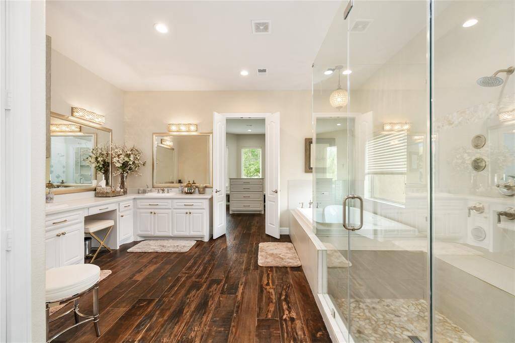 A true spa-like experience awaits in the luxurious en suite. Crisp white cabinetry, dual sinks, and a dedicated vanity area bring both beauty and practicality. The oversized step-in shower and soaking tub are bathed in natural light, inviting you to unwind in total comfort.