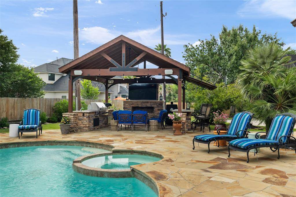 The serene outdoor kitchen is fully equipped for elevated outdoor living—featuring a built-in grill, gas range, sink, bar seating, and even a cozy fireplace. Whether you're hosting a gathering or enjoying a quiet evening under the stars, this space combines function and elegance in perfect balance.