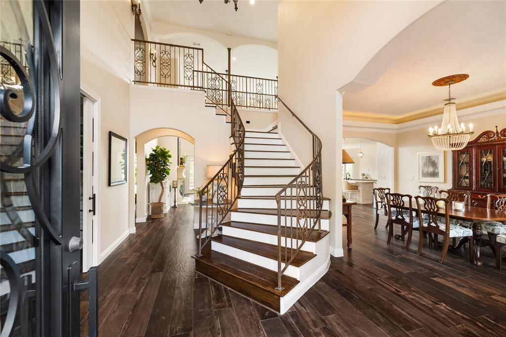 Step inside to a grand welcome—an impressive staircase with graceful iron railings immediately catches your eye, offering a glimpse into the elegant spaces beyond. The entry sets the tone for timeless sophistication.