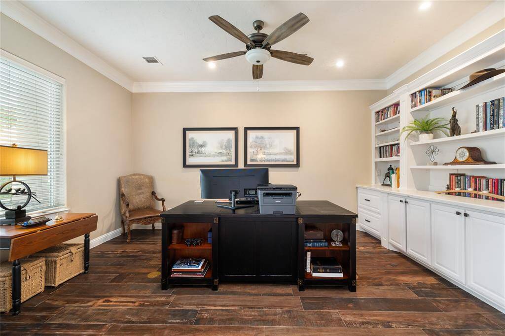 A refined space for focused productivity. The dedicated home office boasts custom built-in cabinetry, expansive windows, recessed lighting, and elegant crown molding—offering both functionality and style in one sleek design.