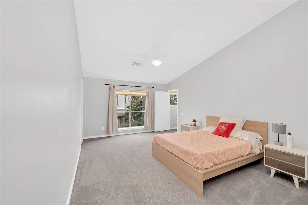 The expansive primary suite has plenty of room for a king size bed, seating area, and more. The large window offers an abundance of natural light. To the left of the window is a walk-in closet with custom built-ins and storage space.