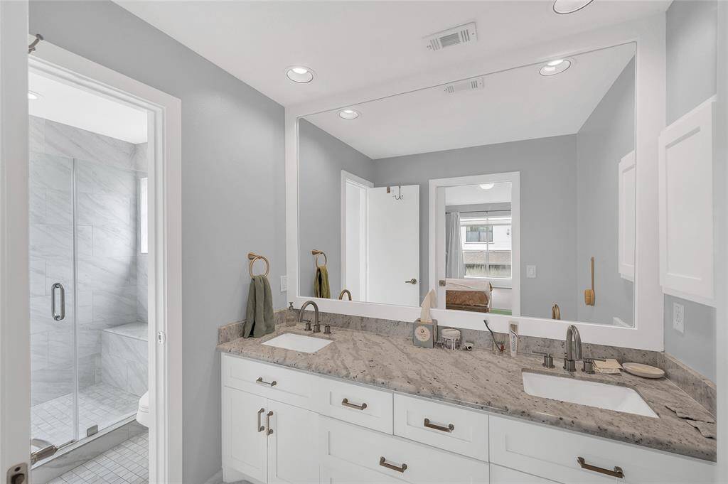 En-suite primary bathroom features double sinks, optimal storage space, a large walk- in shower, designer tile, and sleek fixtures.