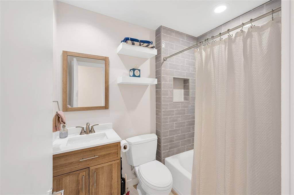 Renovated full bathroom featuring sleek tile, updated fixtures, and modern finishes.