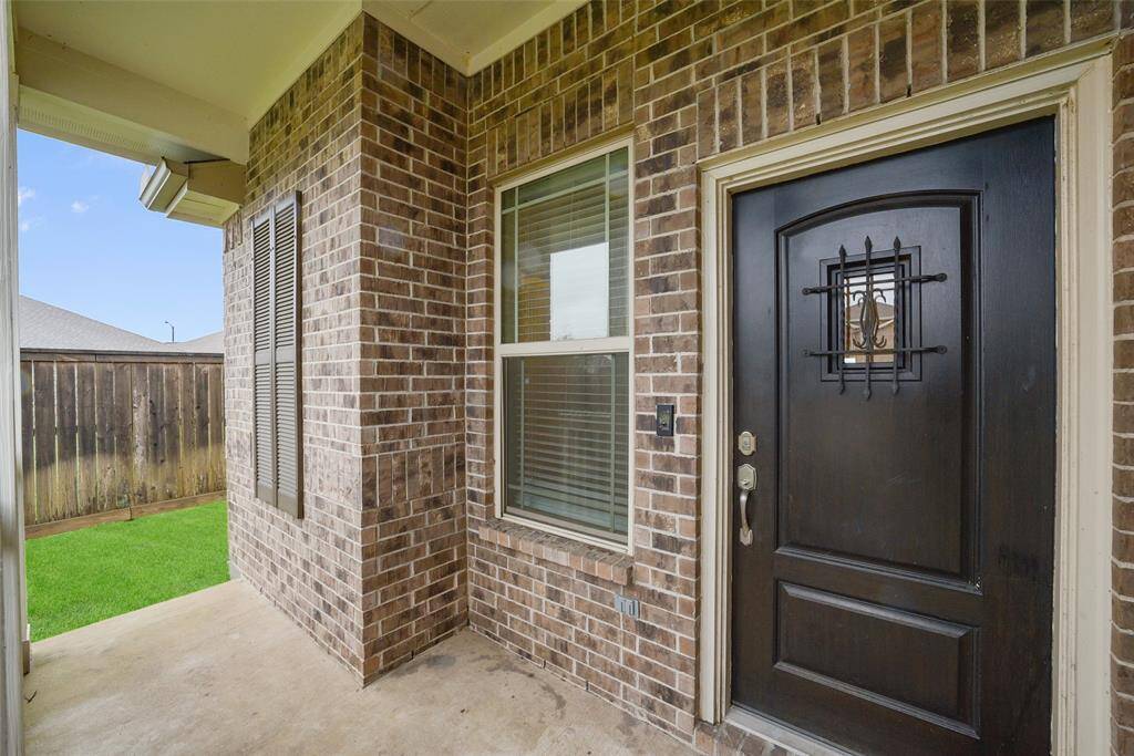 Brick entryway with a sturdy front door featuring decorative ironwork.