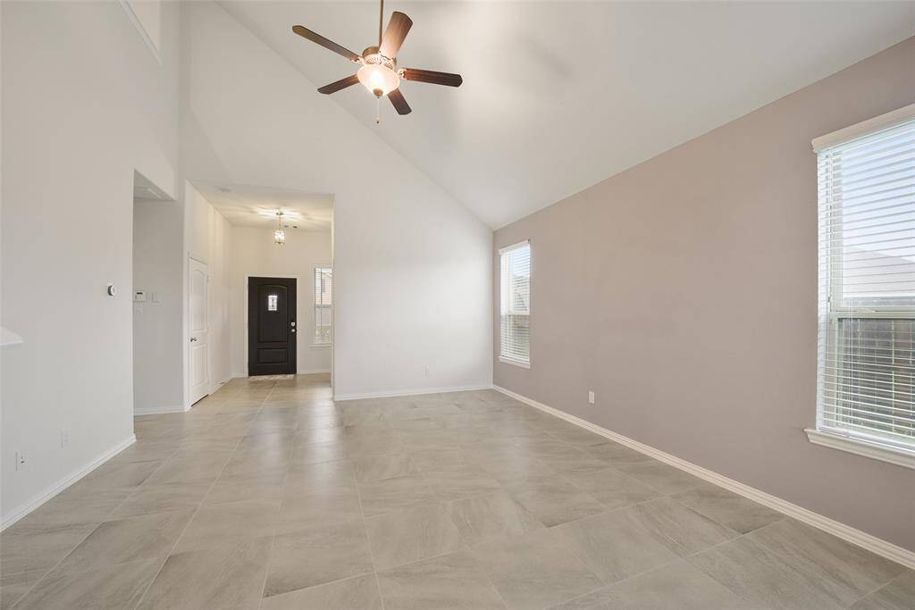 The family room features vaulted ceilings, neutral tile flooring, and ample natural light from large windows.