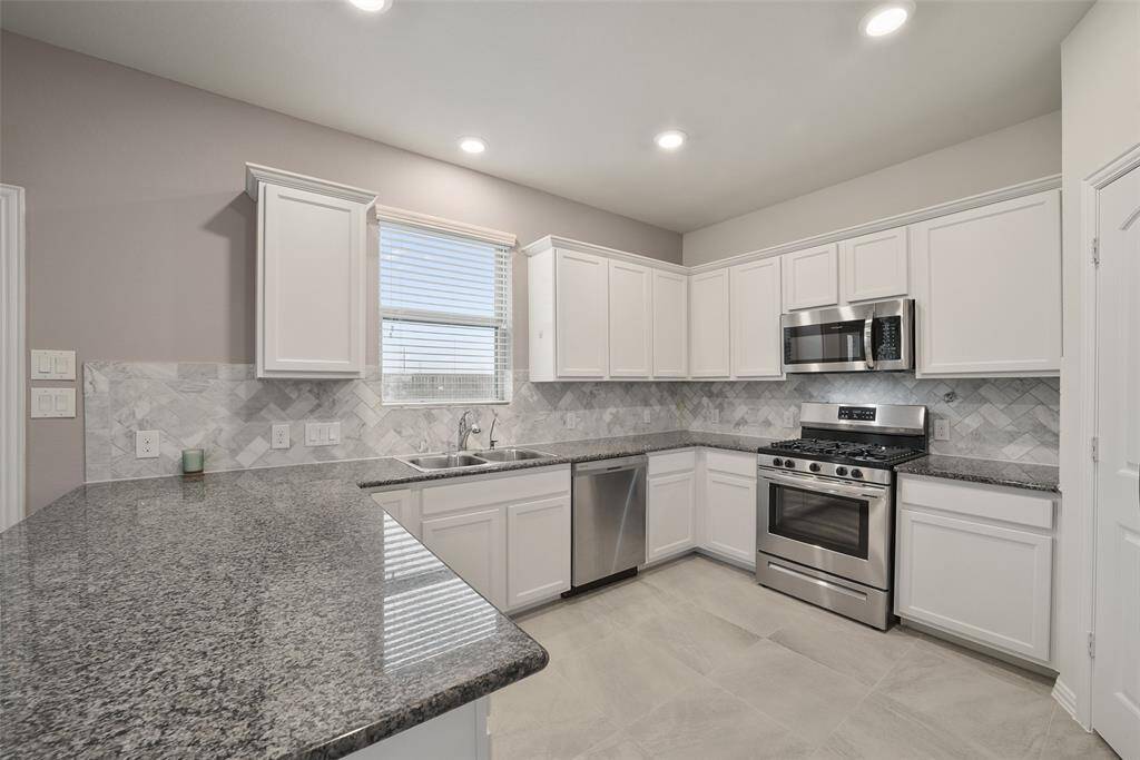 The space is well-lit with recessed lighting and includes a stylish tile backsplash.