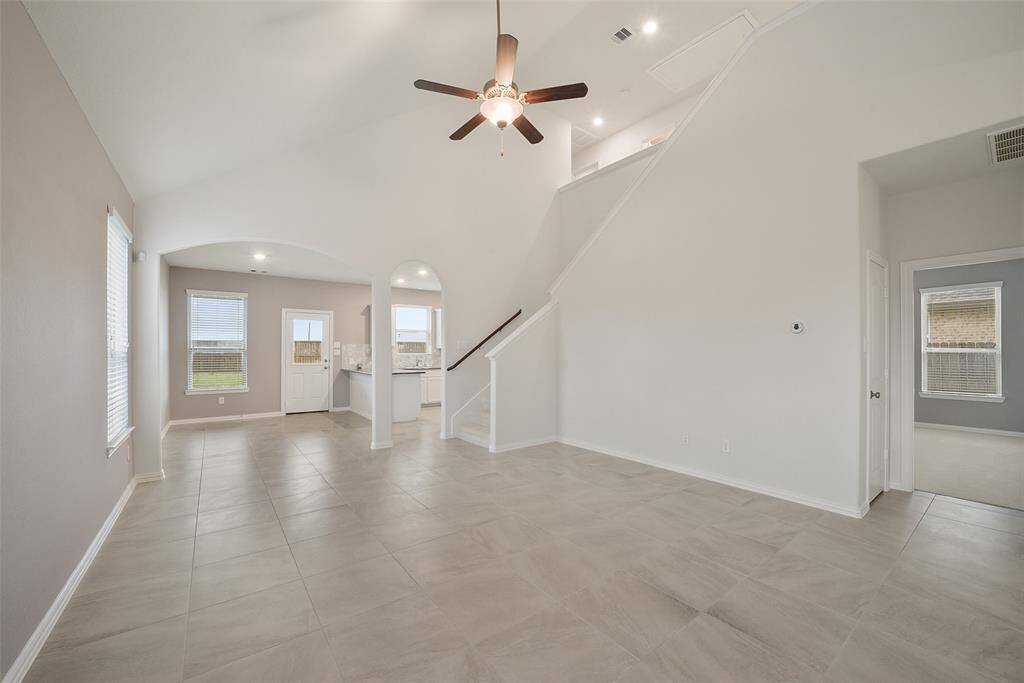 The open layout of the family room leads to a bright kitchen, and a staircase leads to upper-level living.