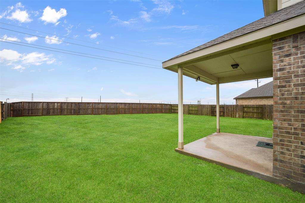 The well-maintained backyard with a lush green lawn features a covered patio area, ideal for outdoor relaxation.