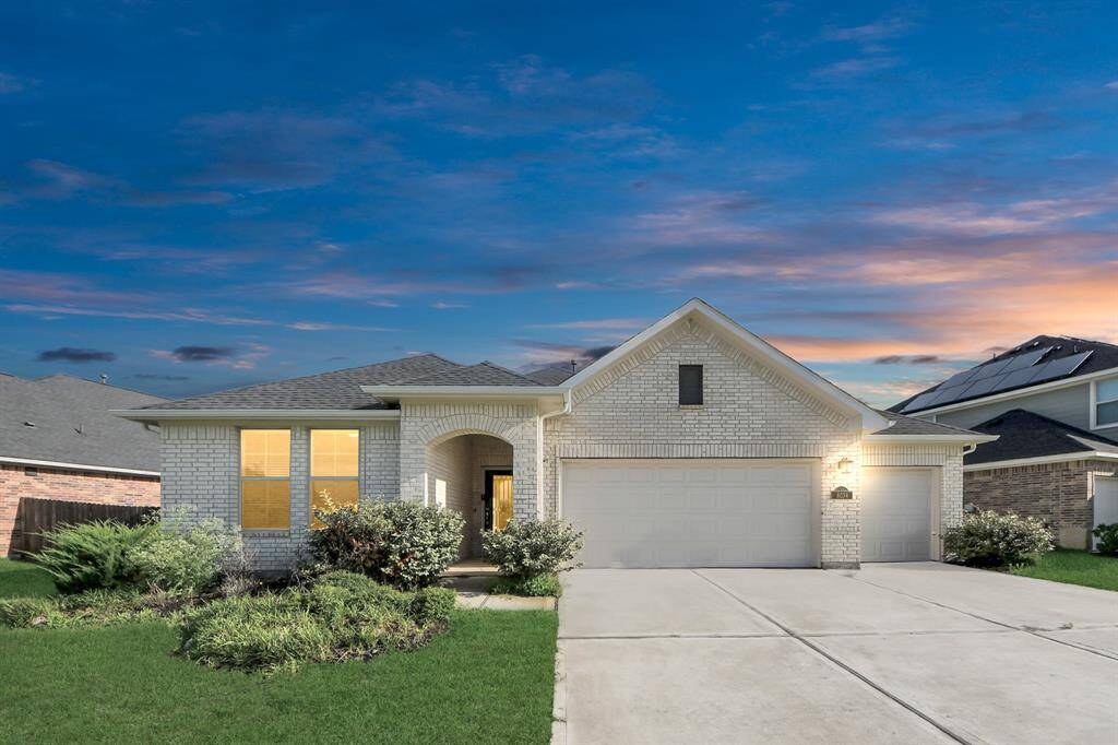 Night view of the front elevation of the house highlighting 3 car garage and white brick.
