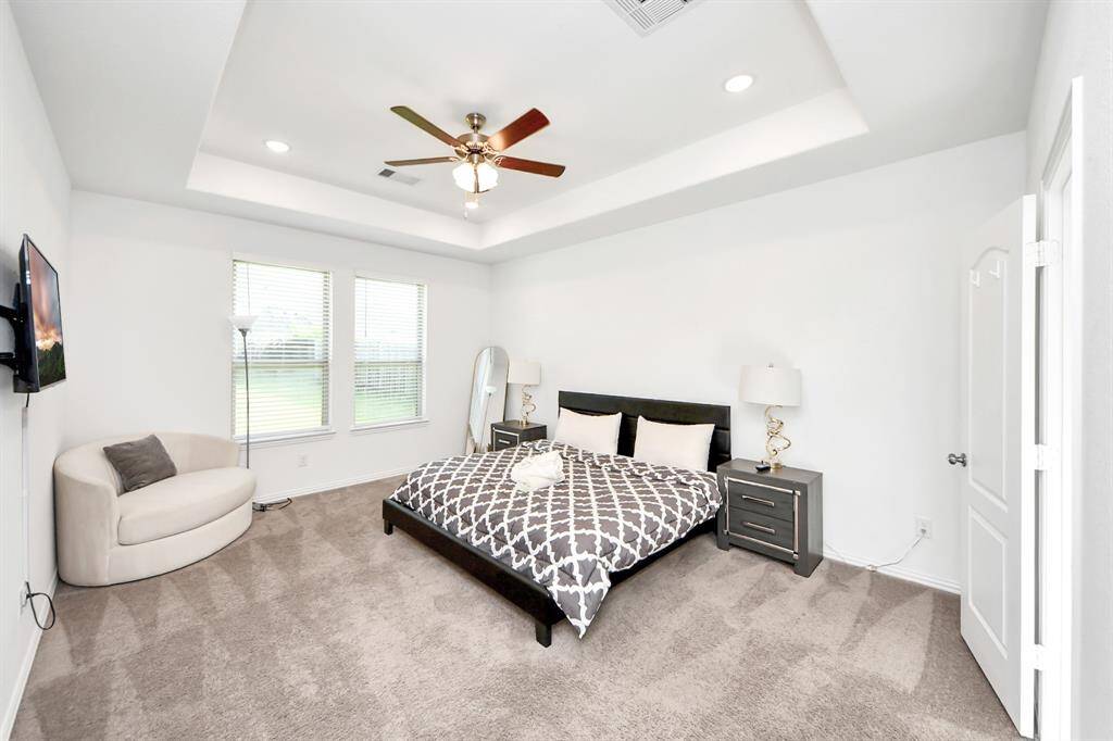 Large primary suite with large windows and bolted ceilings.