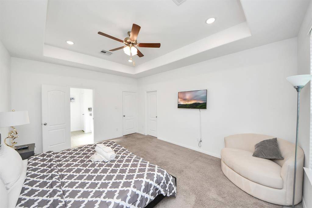 Large primary suite with bolted ceilings and fan.