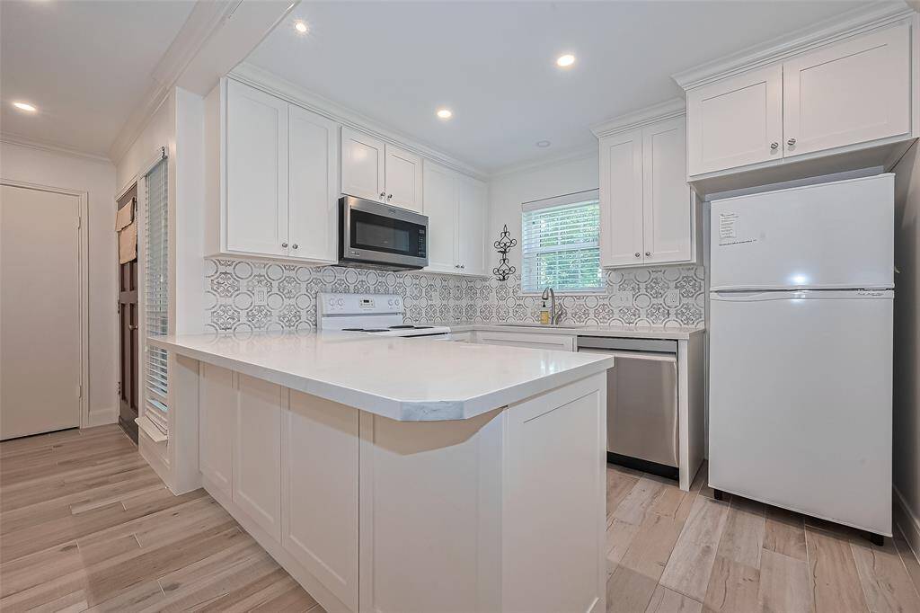Stunningly updated kitchen with Quartz counters, beautiful white cabinetry, breakfast bar, tile flooring, & huge undermount stainless sink!