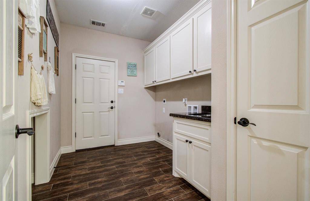 In-home laundry / utility room, upgraded with built-in sink, above full size clothes washer and dryer is additional storage cabinetry and linen closet.