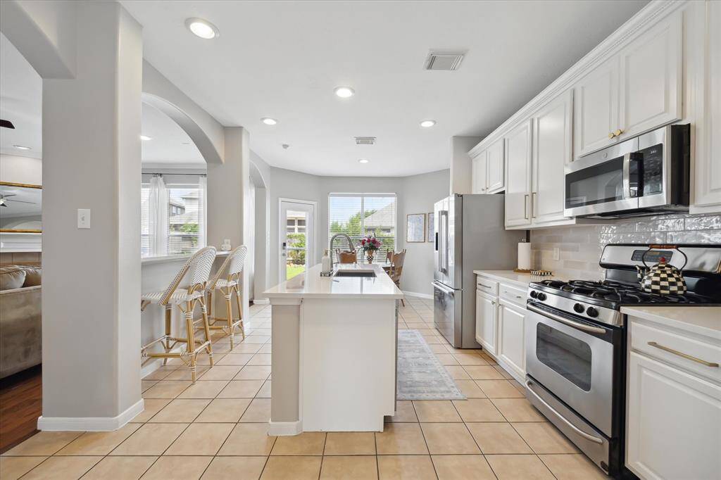 Designer kitchen remodeled in 2025 with new quartz countertops, painted cabinetry, island, and breakfast bar
