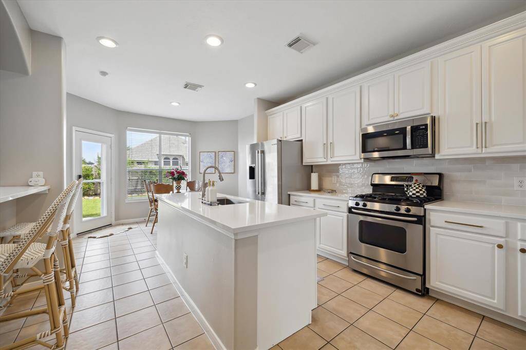 Designer kitchen remodeled in 2025 with new quartz countertops, painted cabinetry, island, and breakfast bar