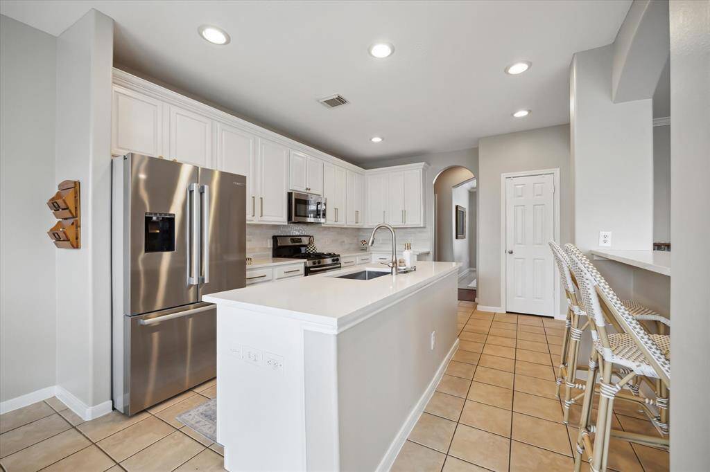 Designer kitchen remodeled in 2025 with new quartz countertops, painted cabinetry, island, and breakfast bar