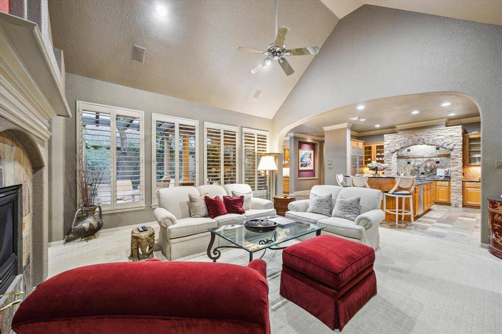 Open living area with soaring ceilings, large built in entertainment system, views of backyard, and double gas fireplace, joined with sunroom.