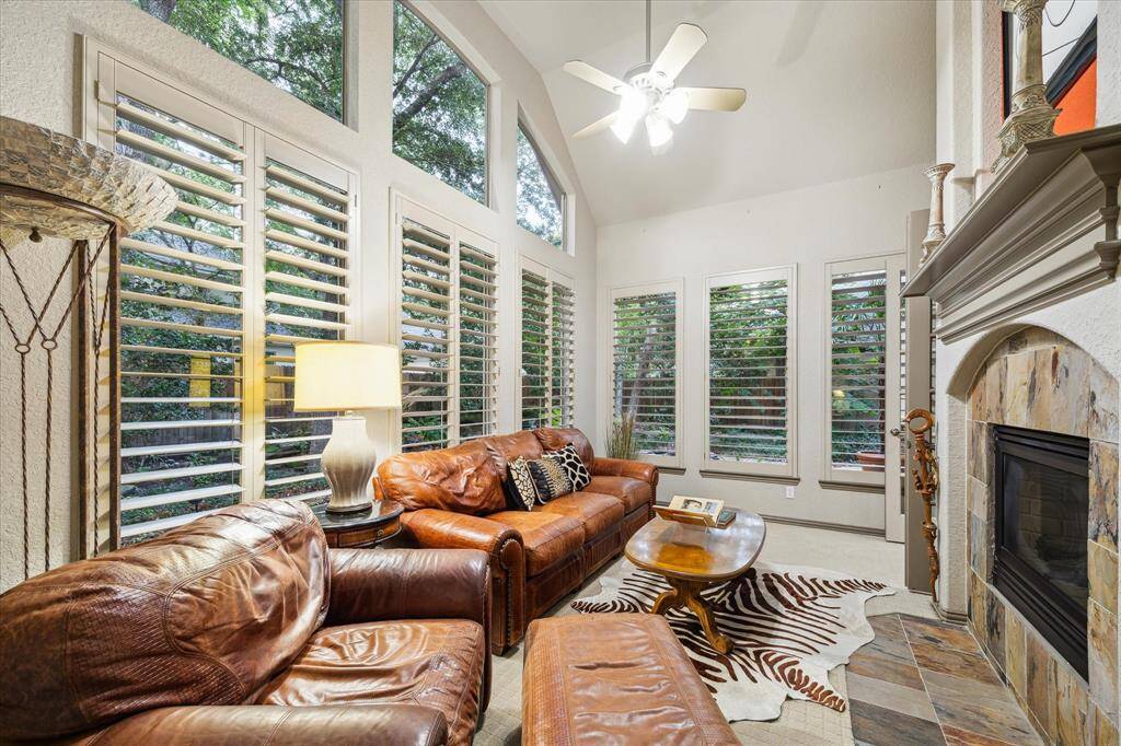 Sunroom with double gas fireplace behind open living room, with two sets of french doors on either side of fireplace.