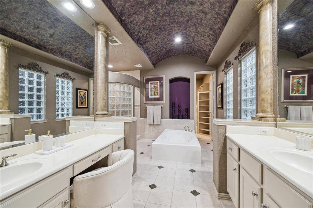 Master bath with dual sinks opposite each other, separate bathtub, and walk in shower. Door into master dual closet area.