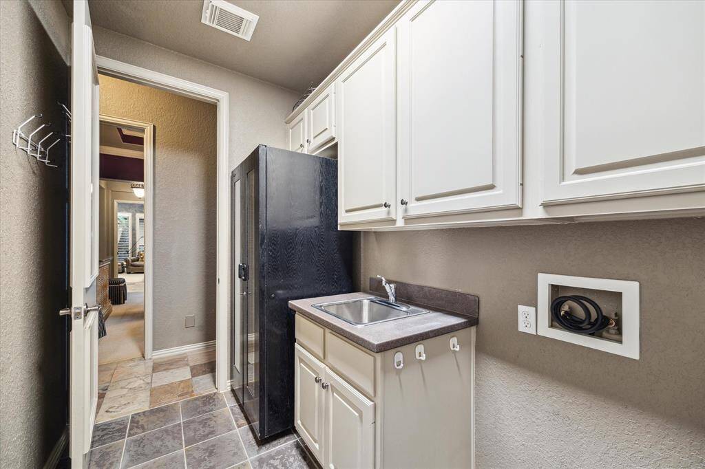 utility room with sink, large wine storage/refrigeration, full-size washer/dryer and plenty of storage space. Enter from back hallway and also from master closet.