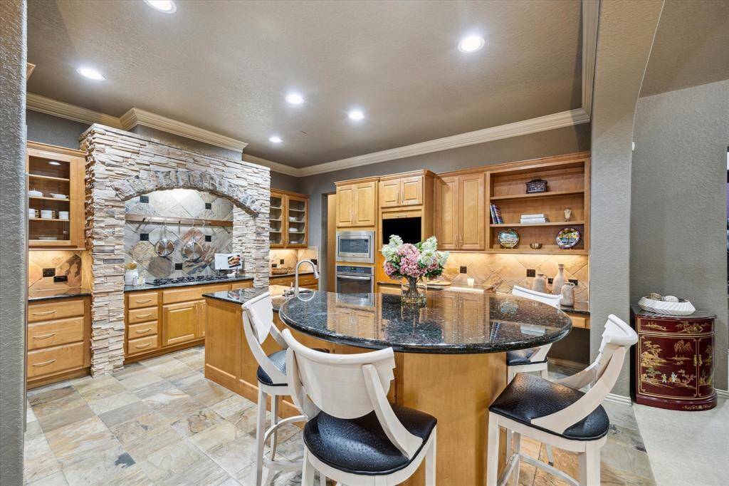Large, open kitchen with breakfast bar, stainless steel appliances, cabinet lighting, gas cooktop
