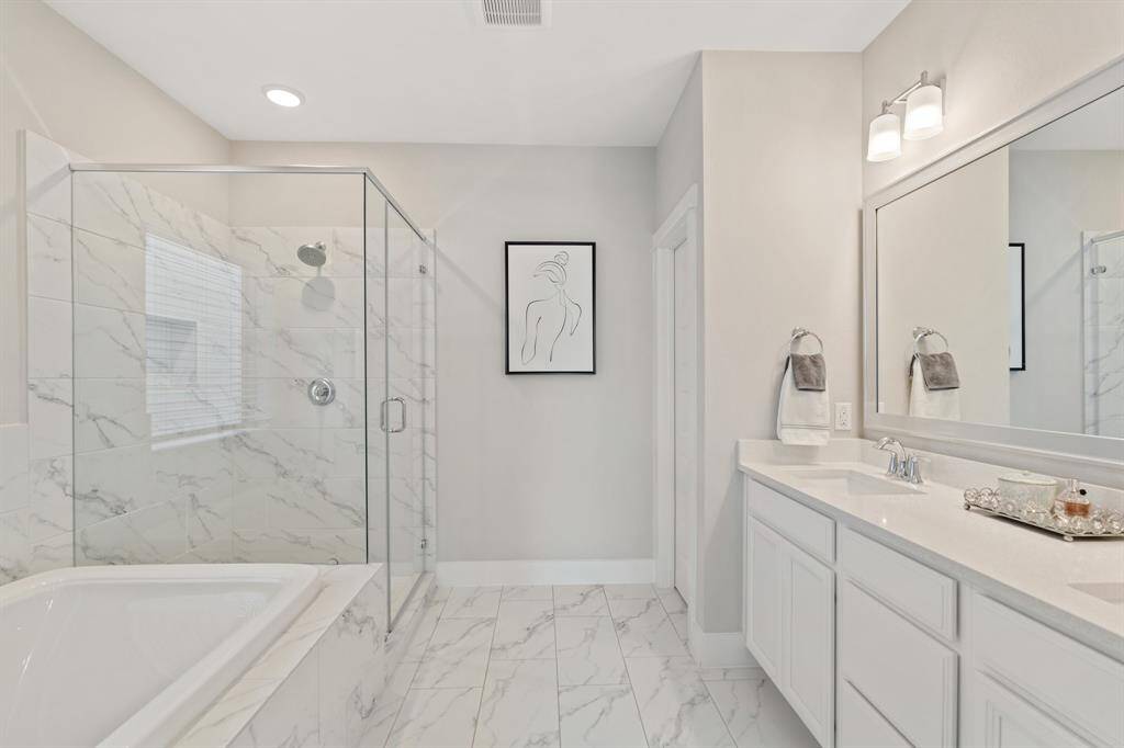 A spa-like bath with dual sinks, quartz counters, a walk-in shower, linen storage, and a private water closet.
