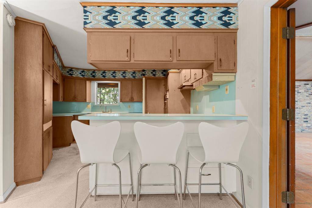 Original solid wood cabinetry and mod wall paper in kitchen.