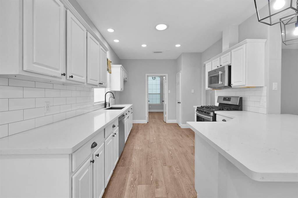 The kitchen features updated white quartz counters and a classic white subway tile backsplash.