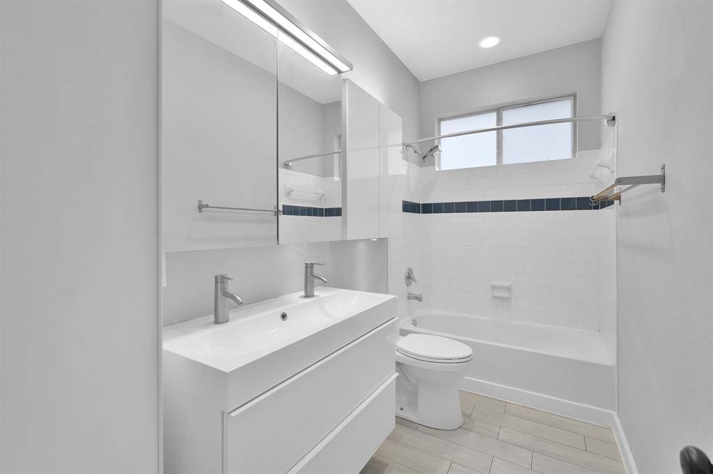 The secondary bath includes double sinks and built-in cabinetry for added storage and convenience.